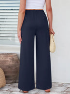 Close up of the secure flat lock stitching and flexible elastic waistband on CLOTHRA wide leg streetwear trousers. in Dark Blue color Back side view