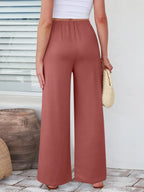 Close up of the secure flat lock stitching and flexible elastic waistband on CLOTHRA wide leg streetwear trousers. in color Brunt Coral Back side view