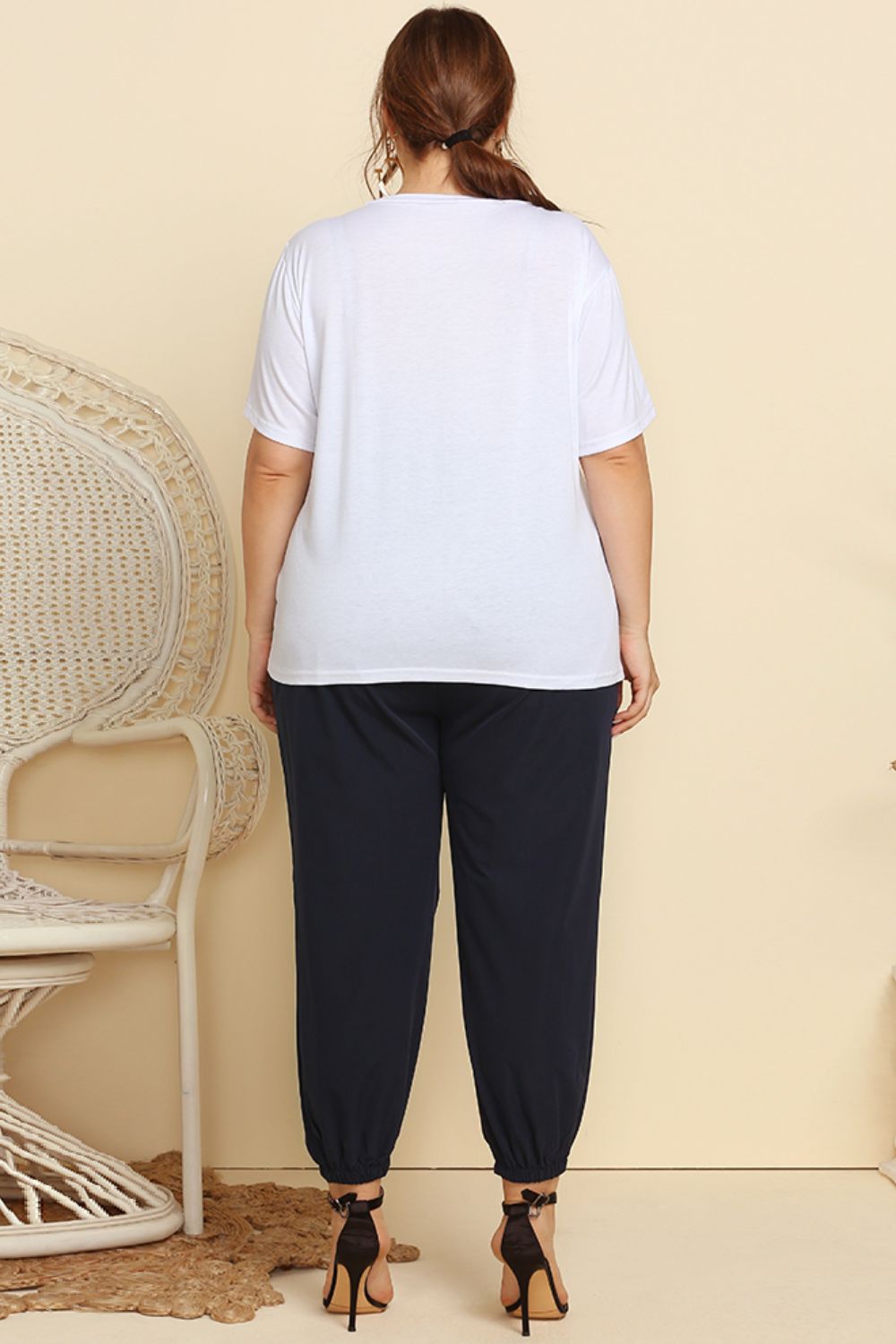 CLOTHRA women's plus size matching two piece streetwear tracksuit featuring a graphic tee and belted paperbag joggers with frill waist. in a Back side