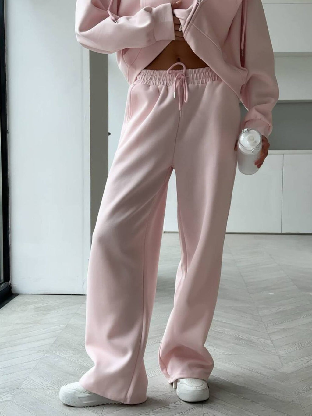 Close up shot of the secure side pocketing, flexible elastic waistband, and cuffed ankles on CLOTHRA matching lounge sweatpants. in a color Pink
