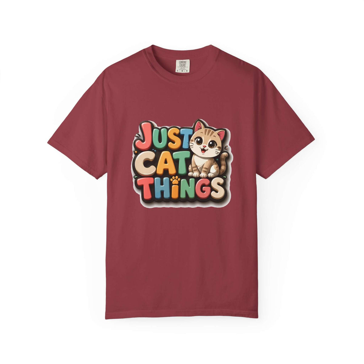 A maroon short-sleeve crewneck t-shirt featuring a colorful graphic on the chest that reads 'JUST CAT THINGS' in playful multicolored letters next to a cute cartoon kitten.