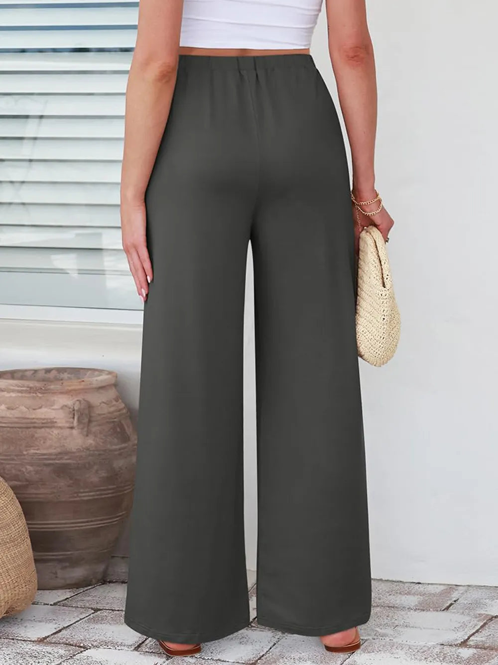 Close up of the secure flat lock stitching and flexible elastic waistband on CLOTHRA wide leg streetwear trousers. in color Grey back side view