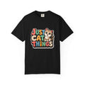 A black short-sleeve crewneck t-shirt featuring a colorful graphic on the chest that reads 'JUST CAT THINGS' in a retro, multi-colored bubble font next to a cute cartoon kitten.