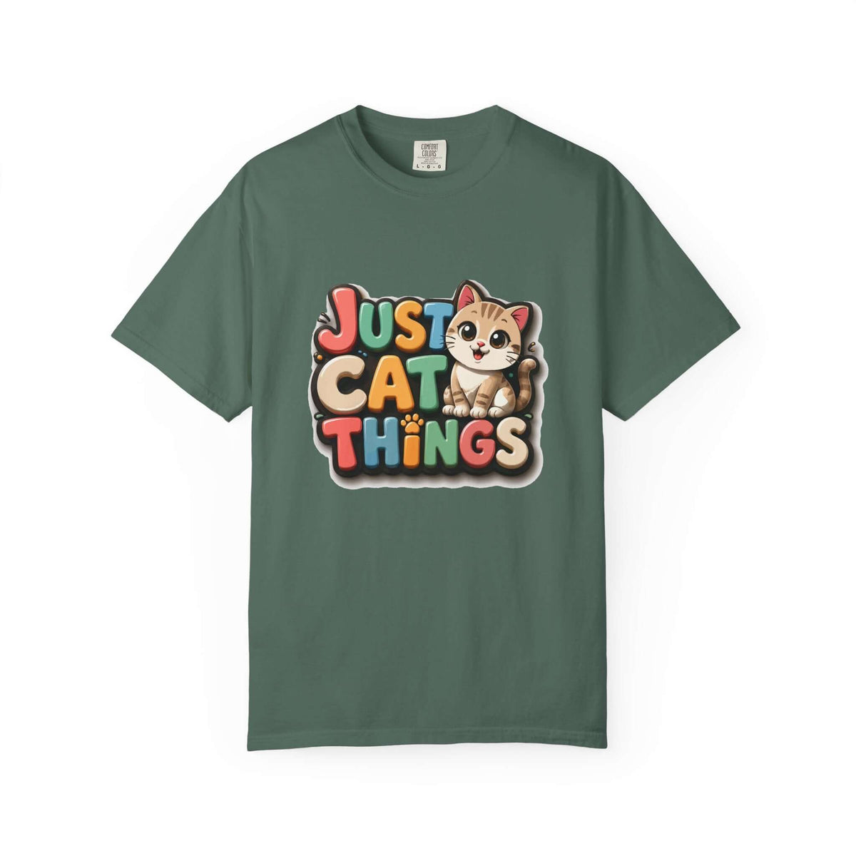 A dark green crewneck t-shirt featuring a colorful graphic on the chest that reads 'JUST CAT THINGS' in a retro, multi-colored bubble font next to a cute cartoon cat.