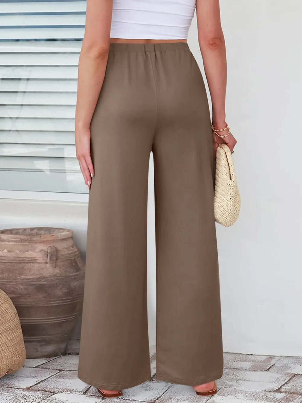 Close up of the secure flat lock stitching and flexible elastic waistband on CLOTHRA wide leg streetwear trousers. in color Taupe Back Side view