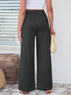 Close up of the secure flat lock stitching and flexible elastic waistband on CLOTHRA wide leg streetwear trousers. in color Dark Grey Back side view