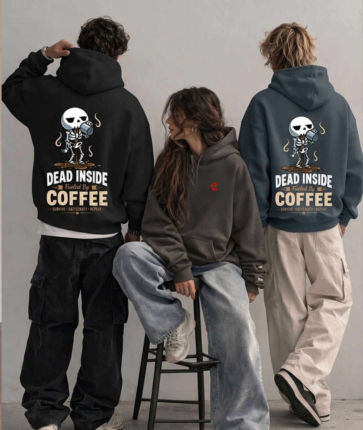 Three models wearing oversized hoodies shown from the back, featuring a skeleton graphic and the text 'DEAD INSIDE COFFEE'. One model wears a black hoodie, another wears a dark gray hoodie with a small red chest logo, and the third wears a slate blue hoodie.