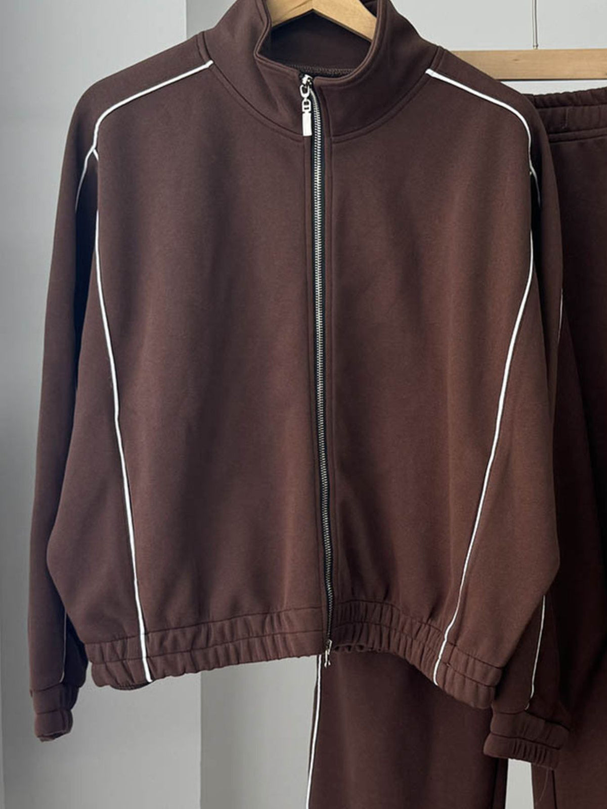 Close up of the smooth front zipper closure and high neck collar profile on CLOTHRA street style outerwear jacket. in a Brown color 