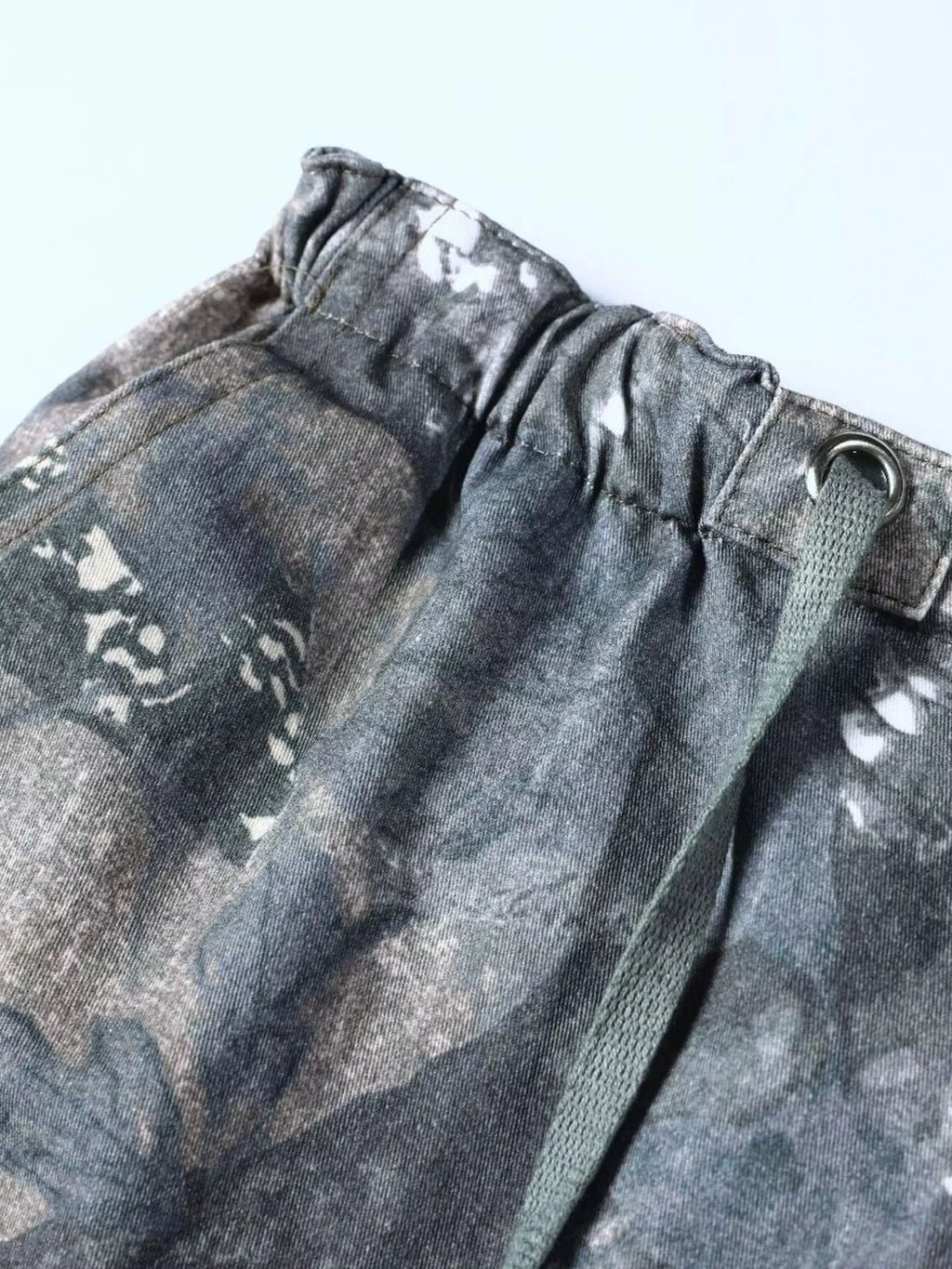 Close up of the adjustable drawstring cords and secure wide elastic waistband on CLOTHRA camo utility trousers.