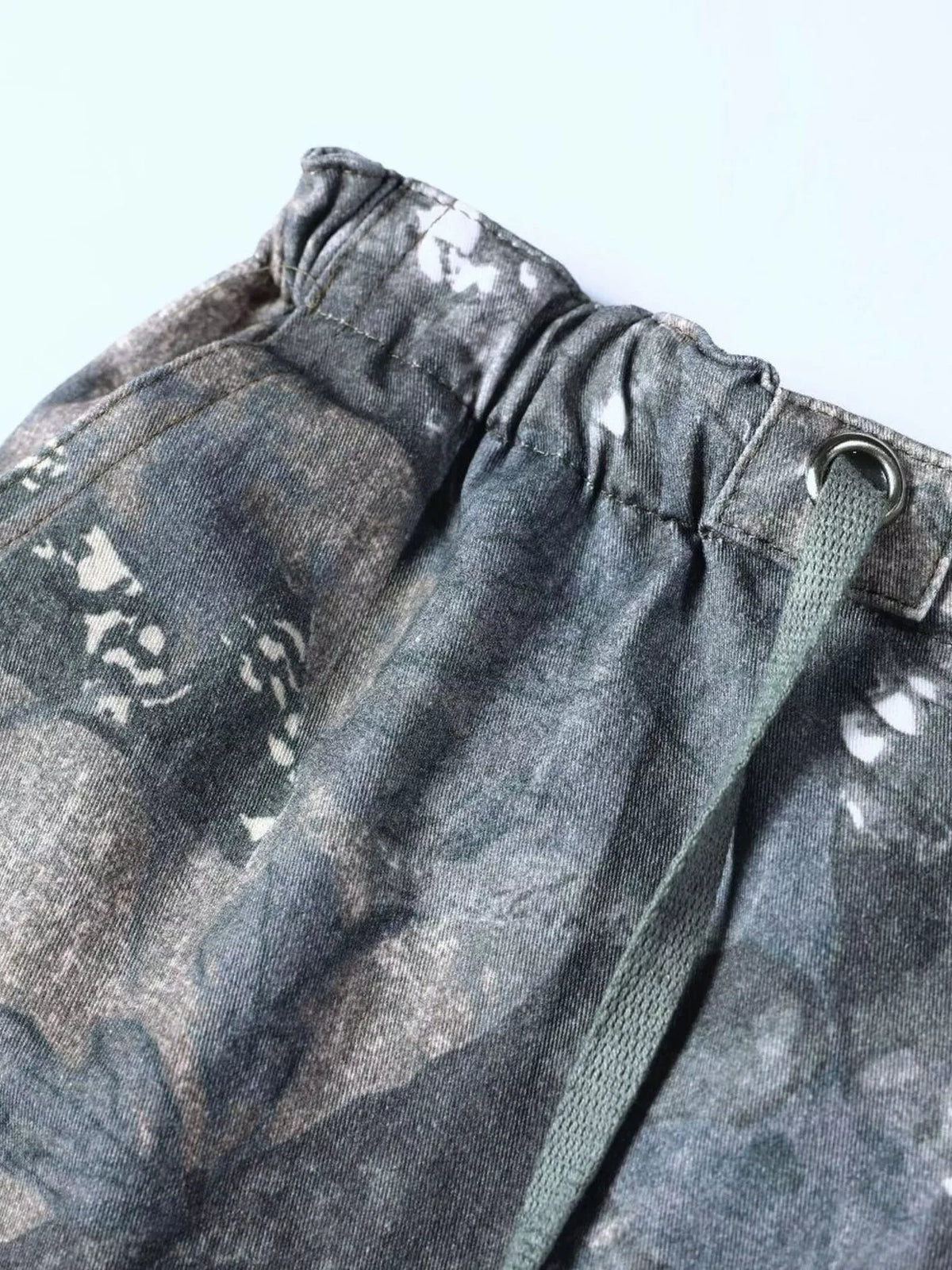 Close up of the adjustable drawstring cords and secure wide elastic waistband on CLOTHRA camo utility trousers.