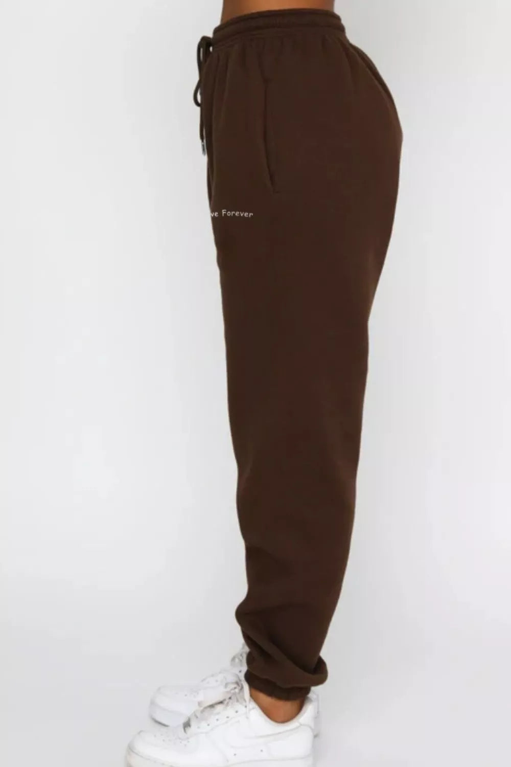 Close up shot of the adjustable drawstring waist and flexible ankle cuffs on CLOTHRA matching track pants. Side view
