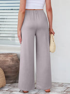 Close up of the secure flat lock stitching and flexible elastic waistband on CLOTHRA wide leg streetwear trousers. in color Light Grey back side view